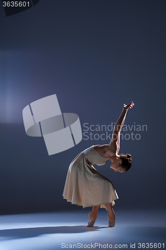 Image of Young beautiful dancer in beige dress dancing on gray background