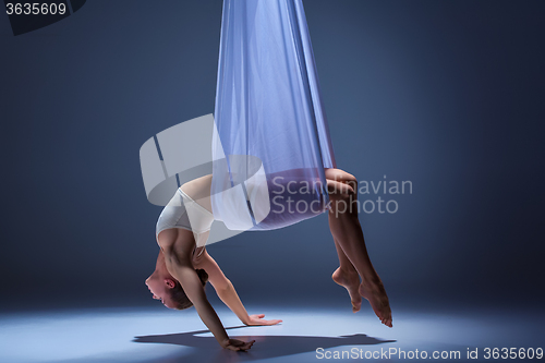 Image of Young beautiful dancer in beige dress posing on gray background