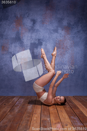 Image of Young beautiful dancer in beige swimwear dancing on lilac background