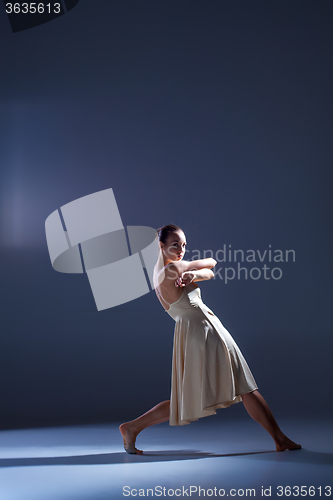 Image of Young beautiful dancer in beige dress dancing on gray background