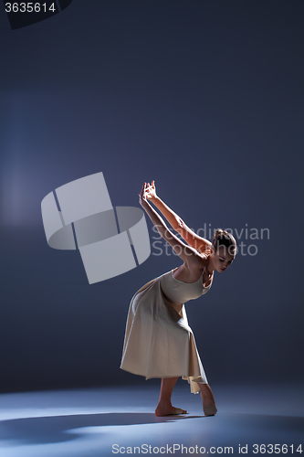 Image of Young beautiful dancer in beige dress dancing on gray background
