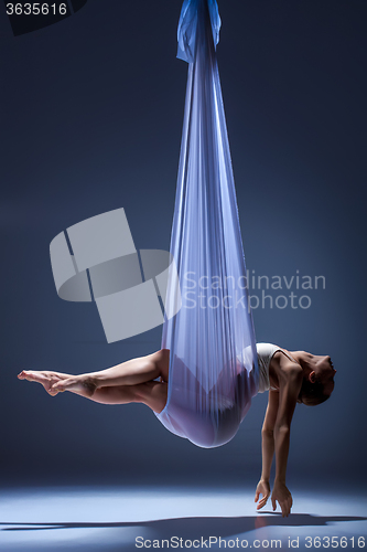 Image of Young beautiful dancer in beige dress posing on gray background