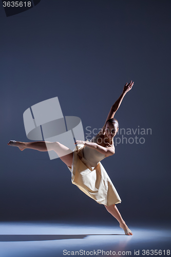 Image of Young beautiful dancer in beige dress dancing on gray background