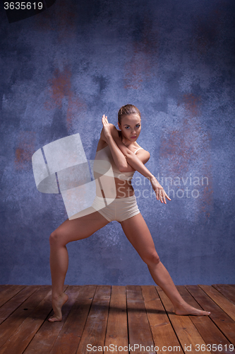 Image of Young beautiful dancer in beige swimwear dancing on lilac background