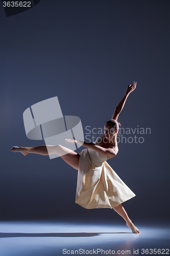 Image of Young beautiful dancer in beige dress dancing on gray background