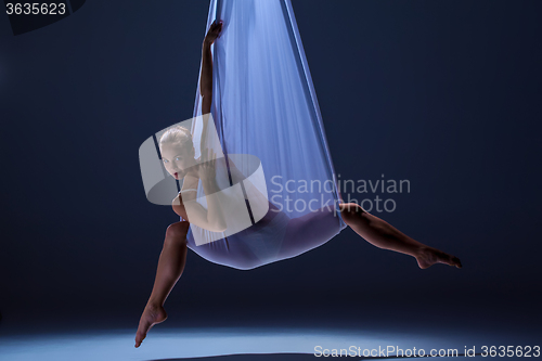 Image of Young beautiful dancer in beige dress posing on gray background