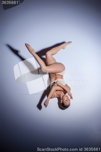 Image of Young beautiful dancer in beige swimwear dancing on lilac background