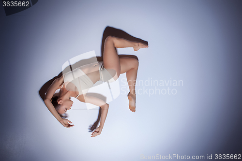 Image of Young beautiful dancer in beige swimwear dancing on lilac background