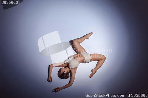 Image of Young beautiful dancer in beige swimwear dancing on lilac background