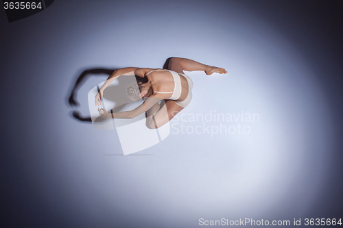 Image of Young beautiful dancer in beige swimwear dancing on lilac background