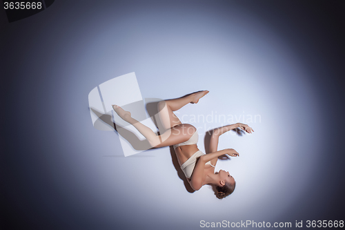 Image of Young beautiful dancer in beige swimwear dancing on lilac background