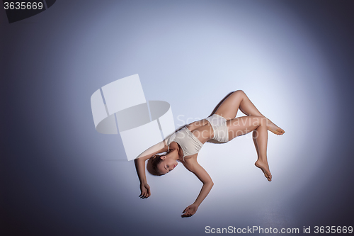 Image of Young beautiful dancer in beige swimwear dancing on lilac background