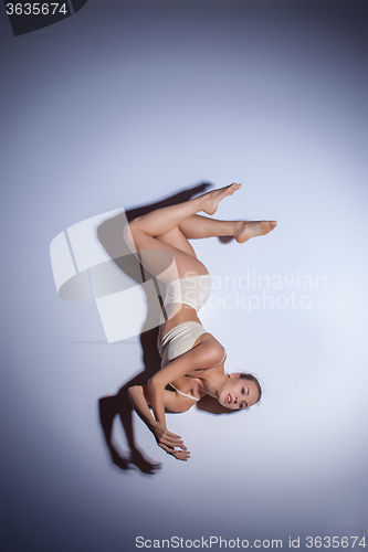 Image of Young beautiful dancer in beige swimwear dancing on lilac background