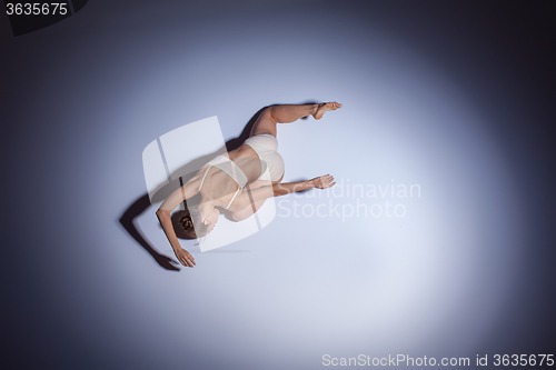 Image of Young beautiful dancer in beige swimwear dancing on lilac background