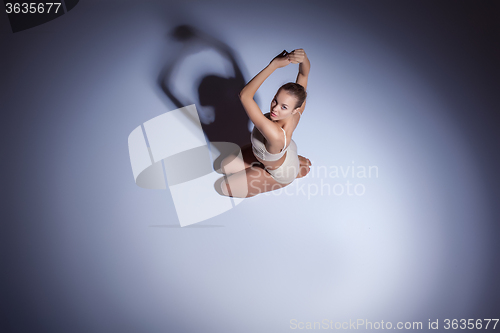 Image of Young beautiful dancer in beige swimwear dancing on lilac background