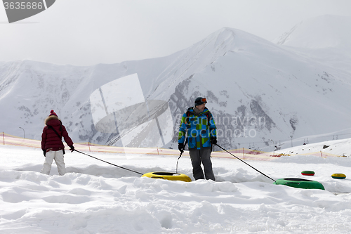 Image of Father and daughter with snow tube at gray day