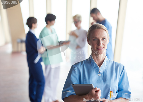 Image of female doctor with tablet computer  standing in front of team