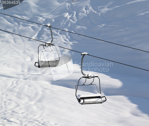 Image of Two chair-lift with snowdrift and off-piste slope in sun morning