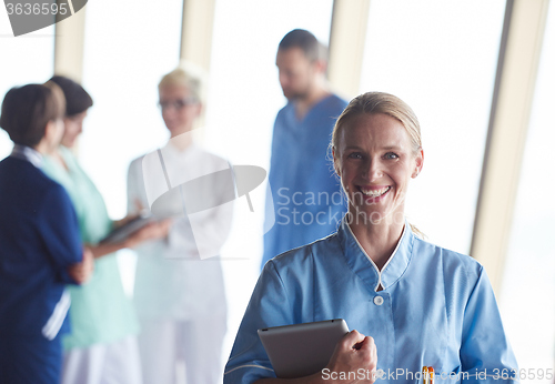 Image of female doctor with tablet computer  standing in front of team