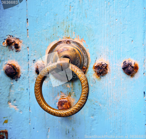 Image of rusty metal nail dirty stripped paint in the blue wood door and 