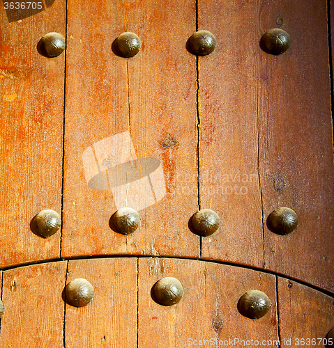 Image of nail dirty stripped paint in the brown wood door and rusty yello