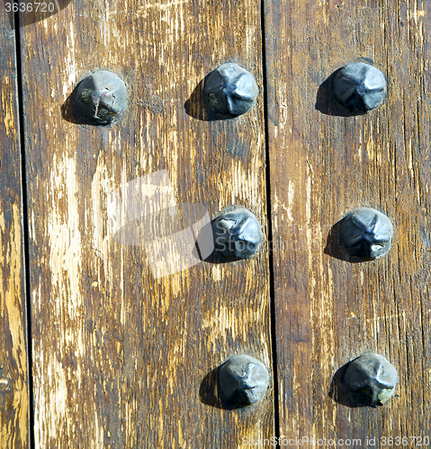 Image of nail dirty stripped paint in the brown wood door and rusty yello