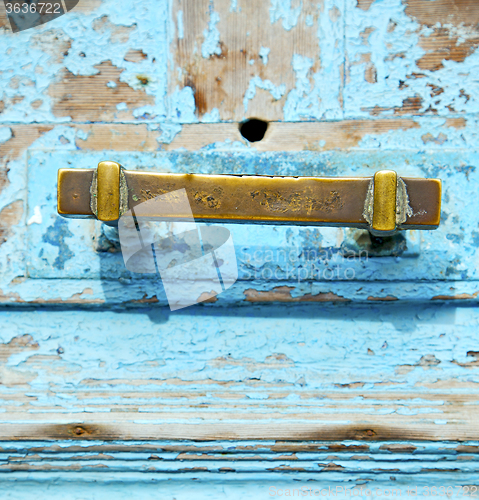 Image of rusty metal     nail dirty stripped paint in the blue wood door 