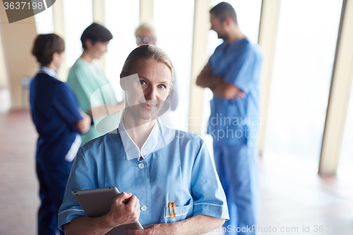 Image of female doctor with tablet computer  standing in front of team