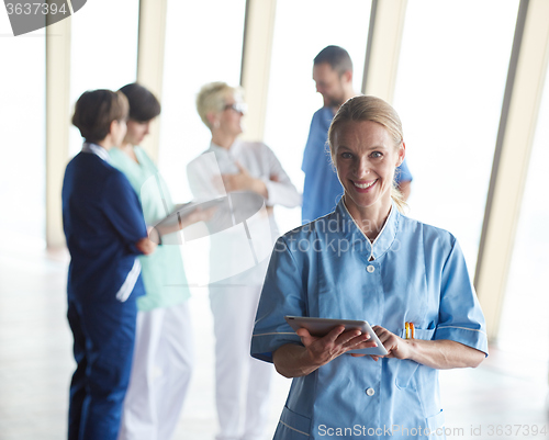 Image of female doctor with tablet computer  standing in front of team