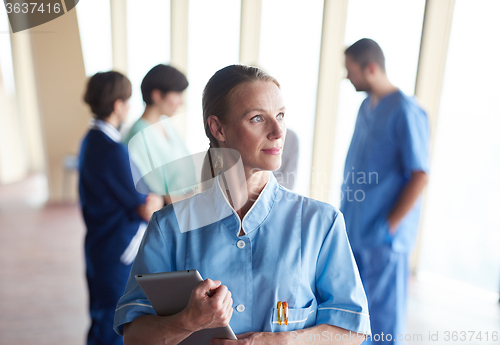 Image of female doctor with tablet computer  standing in front of team