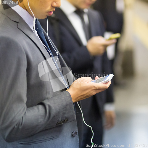 Image of Businessmen using their cell phones on subway.