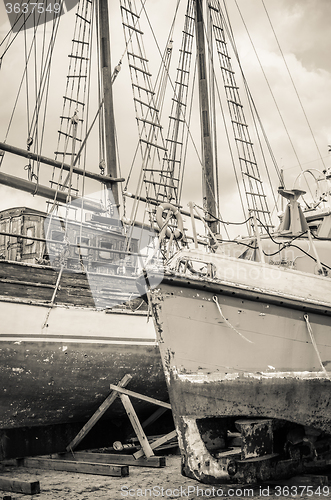 Image of Old collapsing sailboats at the dock, close-up, sepia