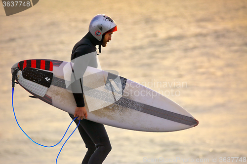 Image of Surfer wearing gath surf helmet and wetsuit at sunrise