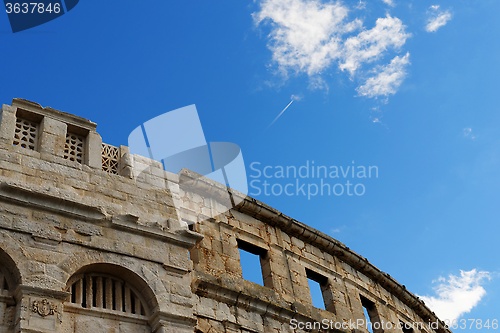Image of Contrail of the jet plane above ancient Roman amphitheater in Pula, Croatia