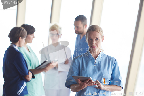 Image of female doctor with tablet computer  standing in front of team