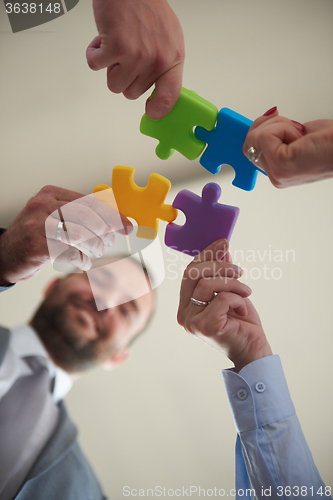 Image of business people group assembling jigsaw puzzle