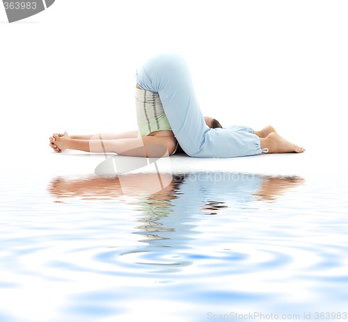 Image of halasana plow pose on white sand