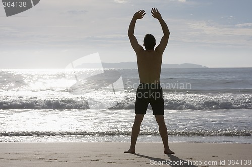 Image of Man doing yoga on the beach