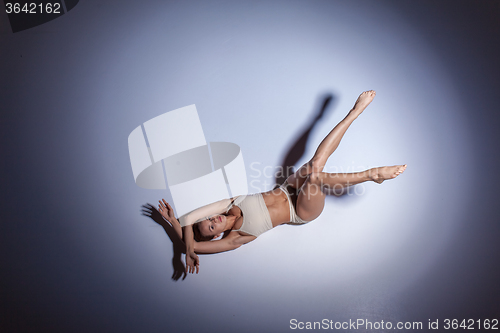 Image of Young beautiful dancer in beige swimwear dancing on lilac background