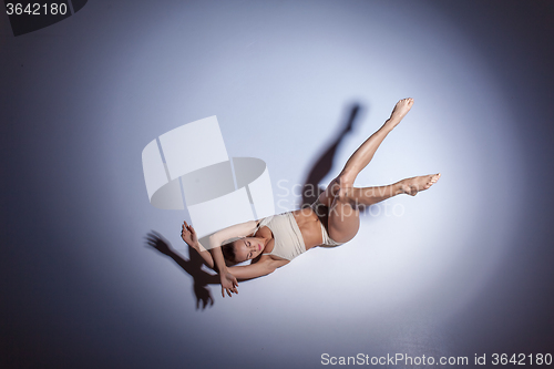 Image of Young beautiful dancer in beige swimwear dancing on lilac background