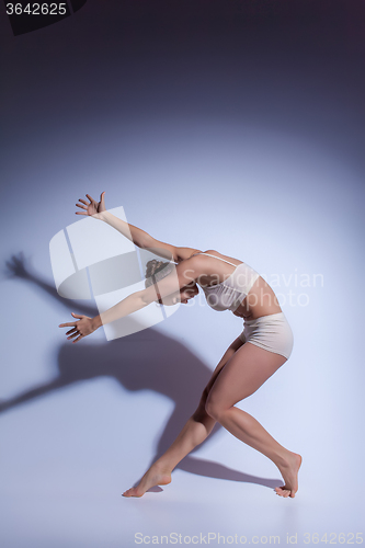 Image of Young beautiful dancer in beige swimwear dancing on lilac background