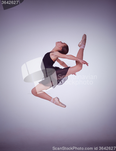 Image of The silhouette of young ballet dancer jumping on a lilac  background.
