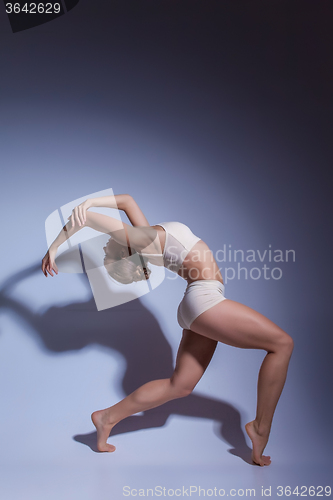 Image of Young beautiful dancer in beige swimwear dancing on lilac background