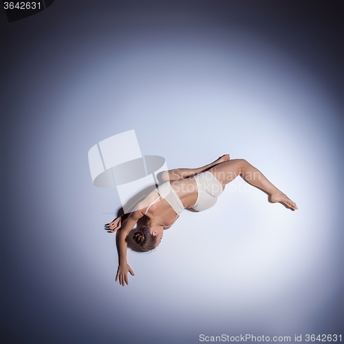 Image of Young beautiful dancer in beige swimwear dancing on lilac background