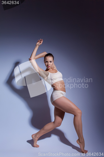 Image of Young beautiful dancer in beige swimwear dancing on lilac background
