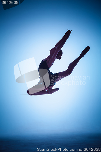 Image of The silhouette of young ballet dancer jumping on a blue background.