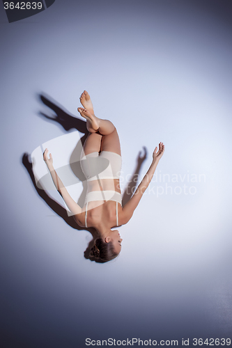 Image of Young beautiful dancer in beige swimwear dancing on lilac background