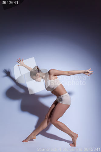 Image of Young beautiful dancer in beige swimwear dancing on lilac background