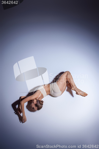 Image of Young beautiful dancer in beige swimwear dancing on lilac background