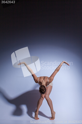 Image of Young beautiful dancer in beige swimwear dancing on lilac background